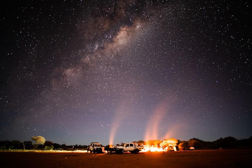 Plants, animals and the land are all intrinsically linked with First Nations groups and their culture. Photo supplied: Andre Sawenko. Photo of outback campers at night, by firelight, under a starlit sky.