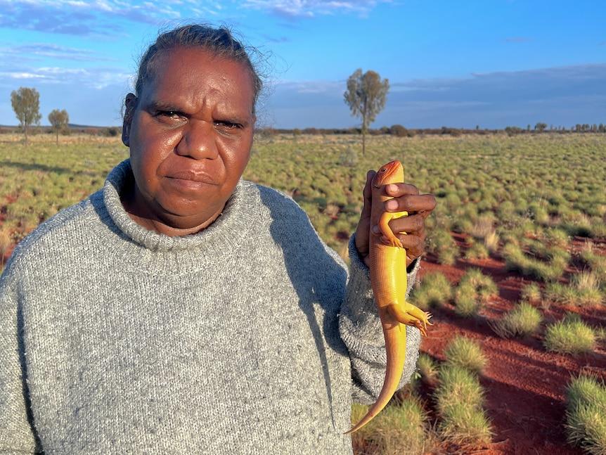 Warlpiri ranger Christine Ellis is part of an Indigenous-led program protecting great desert skinks. Photo supplied: Indigenous Desert Alliance. Photo of Warlpiri ranger Christine Ellis is part of an Indigenous-led program protecting great desert skinks. Photo supplied: Indigenous Desert Alliance.d-by-Indigenous-Desert-AllianceWarlpiri-ranger-Christine-Ellis-holding-great-desert-skink